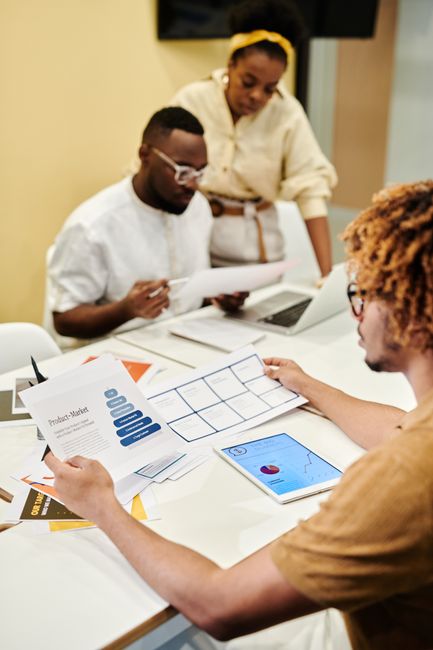 Equipo de trabajo comparando opciones de software en pantallas y documentos impresos