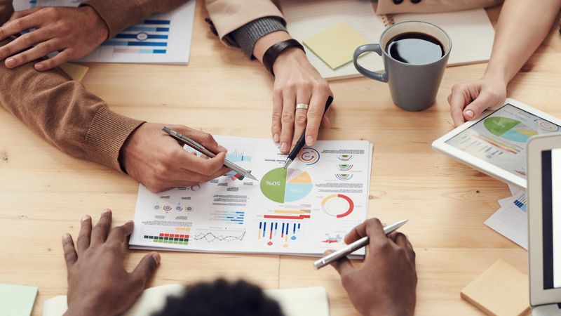 Equipo de trabajo comparando opciones de software en pantallas y documentos impresos